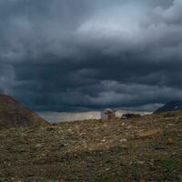 Old climbing house in the mountains under a stormy sky. Empty mountaineering camp. Authentic mountain dramatic landscape in the Altai Mountains. photo