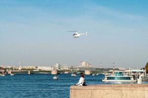 White helicopter of the city administration over the Neva river in St. Petersburg photo