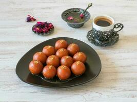 Indian sweets. Traditional sweet Gulab Jamun on a white wooden table. photo