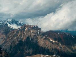 increíble oscuro nube a el parte superior de el montaña. maravilloso dramático paisaje con grande Nevado montaña picos encima bajo nubes atmosférico grande nieve montaña tapas en nublado cielo. foto