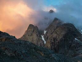 Dangerous gorge. Dramatic fog among giant rocky mountains. Ghostly atmospheric view to big cliff in cloudy sky. Low clouds and beautiful rockies. Minimalist scenery mysterious place. photo