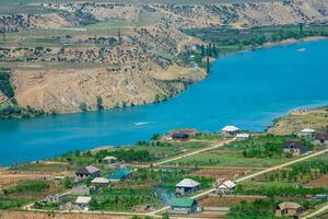 Wide river flows through the mountain village. Mountain summer landscape with Zubutli village. Sulak river. Dagestan. Russia photo