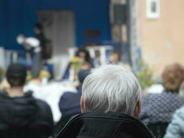 An active pensioner listens to Opera. Back view of the man with a gray hair head in a open air photo