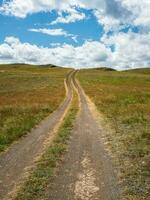 Way to the distance, way over the hill to the sky. Dirt road through the field. photo