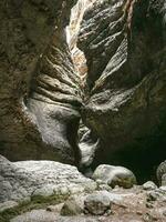 descanso en el roca, el Entrada de un estrecho cueva. interesante rocas formando un estrecho paso en el saltinskij garganta. un único naturaleza reserva en daguestán garganta en montañas paisaje naturaleza. foto
