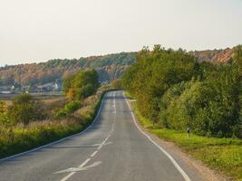 An empty highway country road among beautiful autumn hills. photo