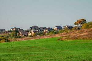 The village in the green hollow. Modern cottage village in a green field. photo