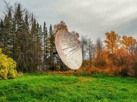 Clásico radio telescopio, un grande satélite plato en un antecedentes de observación bosque y nublado cielo, Radar en el pasado. tecnología concepto, buscar para extraterrestre vida, escuchas telefónicas de espacio. foto