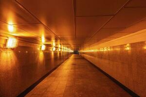 Empty underground passage illuminated with yellow light. photo