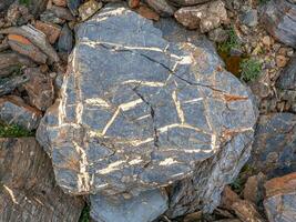 Gold-veined stone, a natural mineral Textured vivid geological background with rude stones. Amazing mineral. Piece of rock. photo