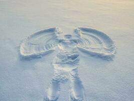Snow angel made in the white snow in the evening. photo