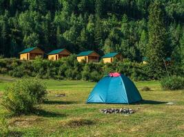 Collective camping in an eco-friendly green place. Tourist complex, wooden guest houses against the background of fir-covered high mountains. photo