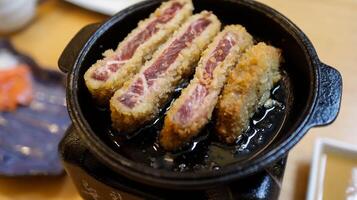 Gyukatsu or gyu katsu is a crispy deep fried rare beef cutlet served with hot mini grill, from nice medium beef to well done beef, very tender wagyu beef. photo