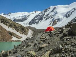 Orange reinforced tent against the background of a glacier on a photo