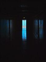 final de oscuro túnel con magia azul ligero. vertical vista. vacío oscuro corredor en hospital laboratorio. azul ligero a el final de un oscuro corredor. foto