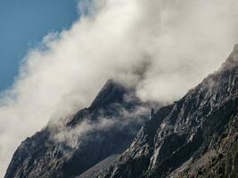 místico montañas. atmosférico paisaje en parte superior de montaña cresta encima grueso bajo nubes hermosa alpino paisaje con montaña rango terminado denso nubes foto