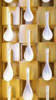 A wall of decoration full of hanging white soup spoon. photo