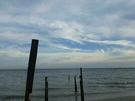 el cielo encima el playa con el sombra de un de madera silueta en pie vertical foto