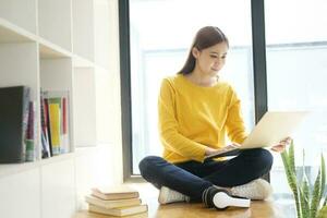 Young woman working or studying online using laptop sitting on the floor. photo