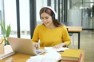 Woman learning online using laptop and writing notes. photo