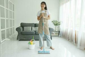 Young woman cleaning floor using mop at home. photo