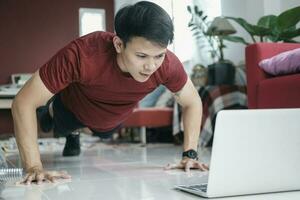 Asian man uses computer tablet to lean plank position. photo