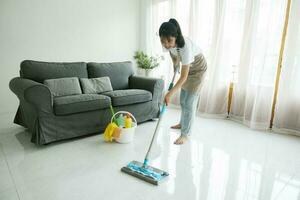 joven mujer limpieza piso utilizando fregona a hogar. foto