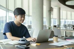 Young collage student using computer and mobile device studying online. photo