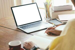 Young woman using computer and writing at home photo