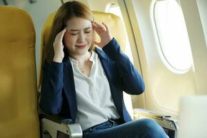 mujer de negocios sufrió dolor de cabeza sentado en avión. foto
