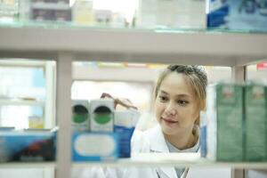 Female pharmacist checking stock inventory in pharmacy. photo