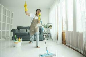 joven mujer teniendo divertido mientras limpieza a hogar. foto