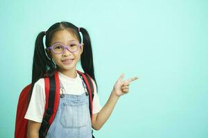 Smiling little girl in glasses pointing finger upward. photo