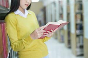 Student standing and reading book at library. photo