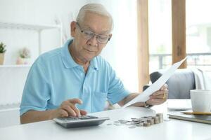 Serious man sitting at table near utility bill and calculating expenses photo
