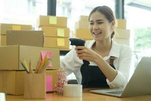 Young asian businesswoman use bar code scanner Scan the barcode on the product box. photo