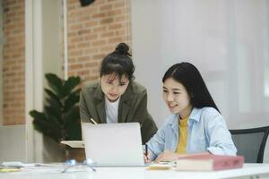 Young asian university students studying learning discuss working on computer. photo