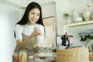 cerca arriba joven asiático mujer de negocios Moda blogger demostración tejido cesta productos con sonriente. foto