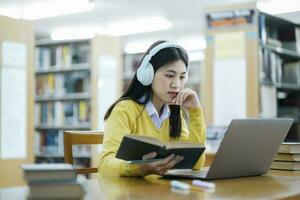 Student sitting and studying with laptop at library. photo