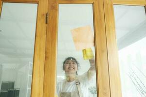 joven asiático mujer limpieza ventana. foto