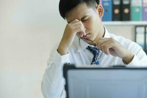Tired and overworked manager sitting in front of computer and trying to concentrate, his eyes are dry and hurt. photo