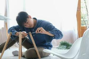 Young man doing DIY work, assembling furniture at home. photo