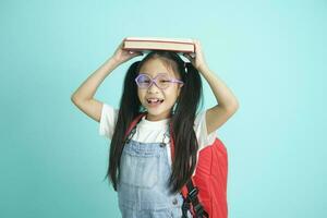 Portrait of happy lazy little girl covering head with book and smiling to camera. photo