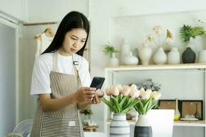 Young asian business owner holding phone and retail package parcel. photo
