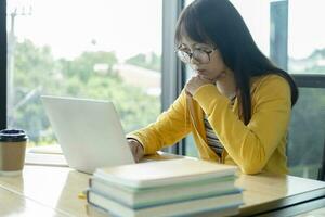 Young collage student using computer and mobile device studying online. photo