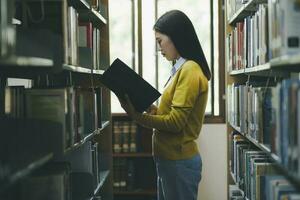 Student standing and reading book at library. photo