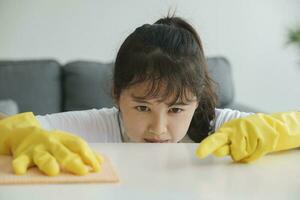 joven mujer limpieza mesa vistiendo guantes a hogar. foto