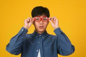 Portrait of asian nerd man with red glasses on yellow background. photo