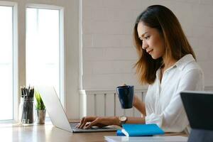 Beautiful woman using laptop at cafe while drinking coffee. photo