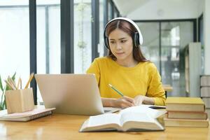 Woman learning online using laptop and writing notes. photo